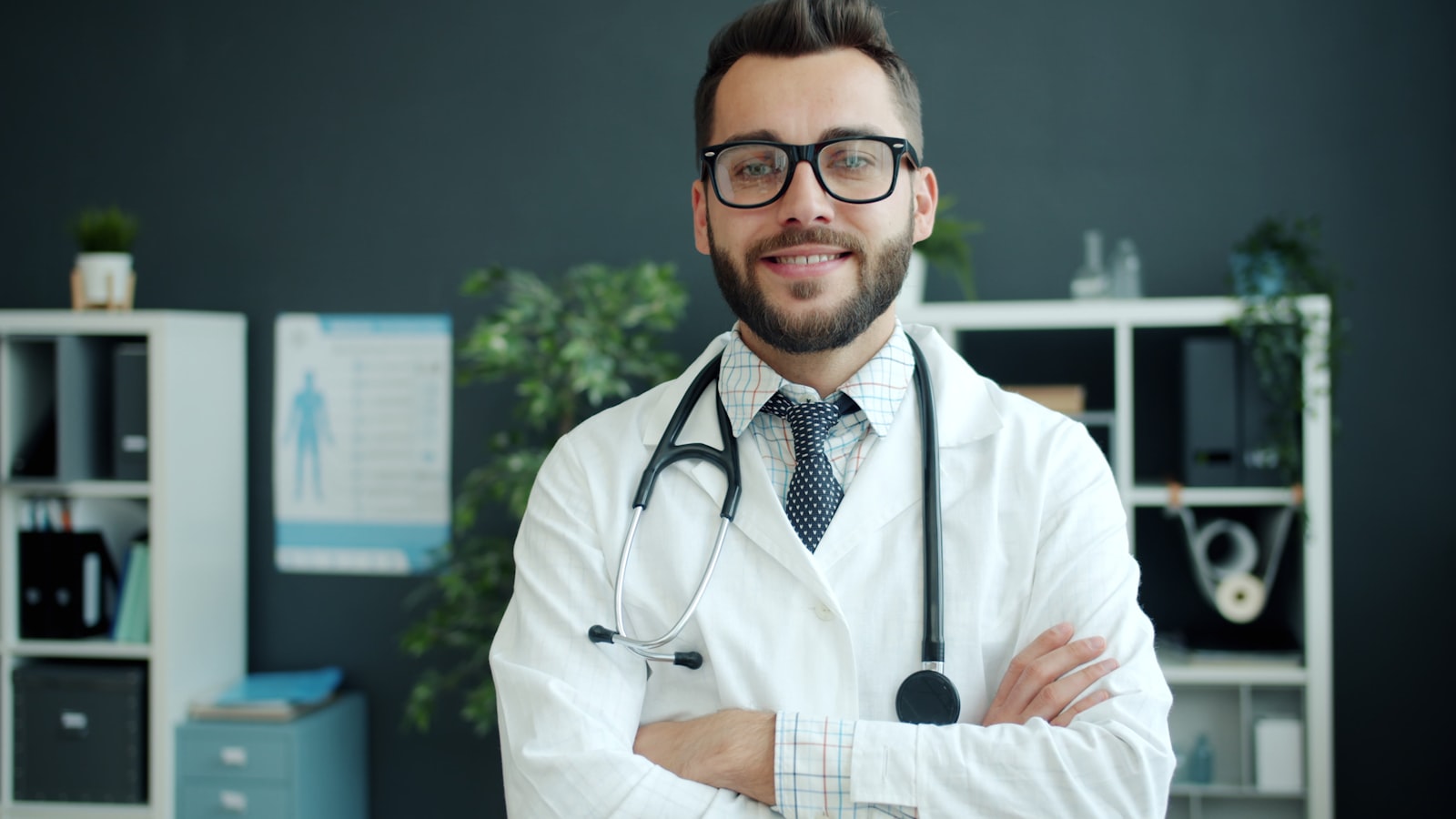 Médico sorridente, de jaleco branco e estetoscópio, em consultório