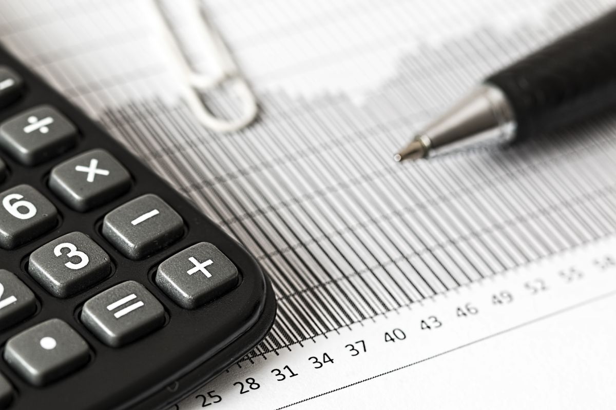 Calculadora, caneta e gráfico financeiro sobre a mesa