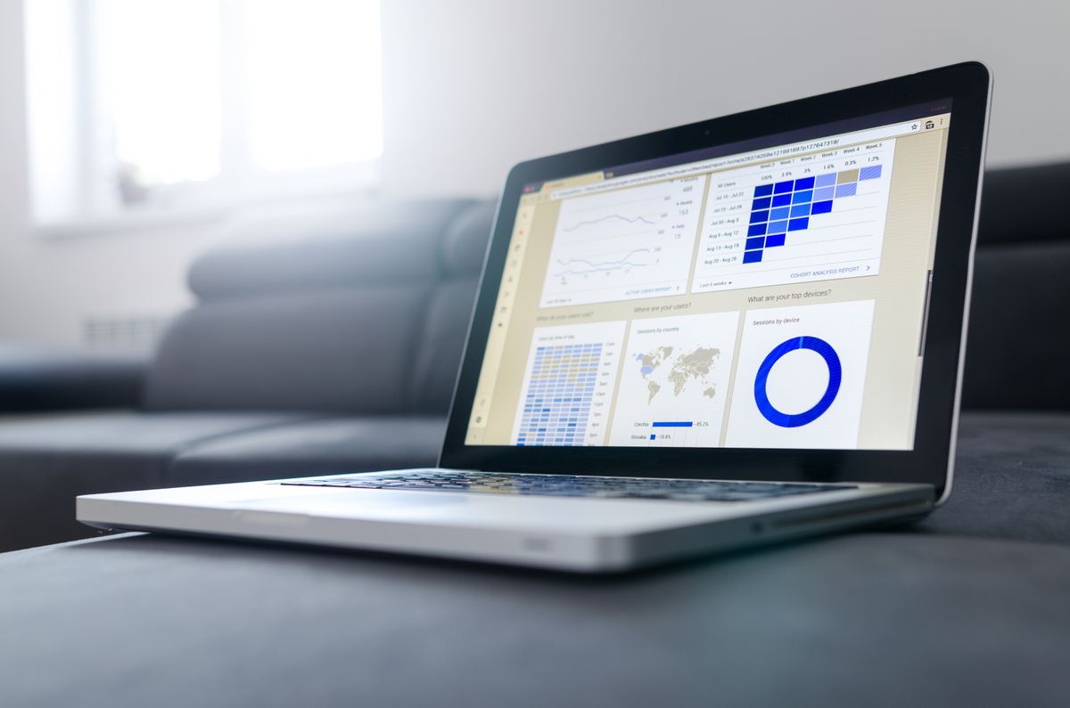 Laptop exibindo um dashboard de indicadores com múltiplos gráficos, mapa e painéis de dados