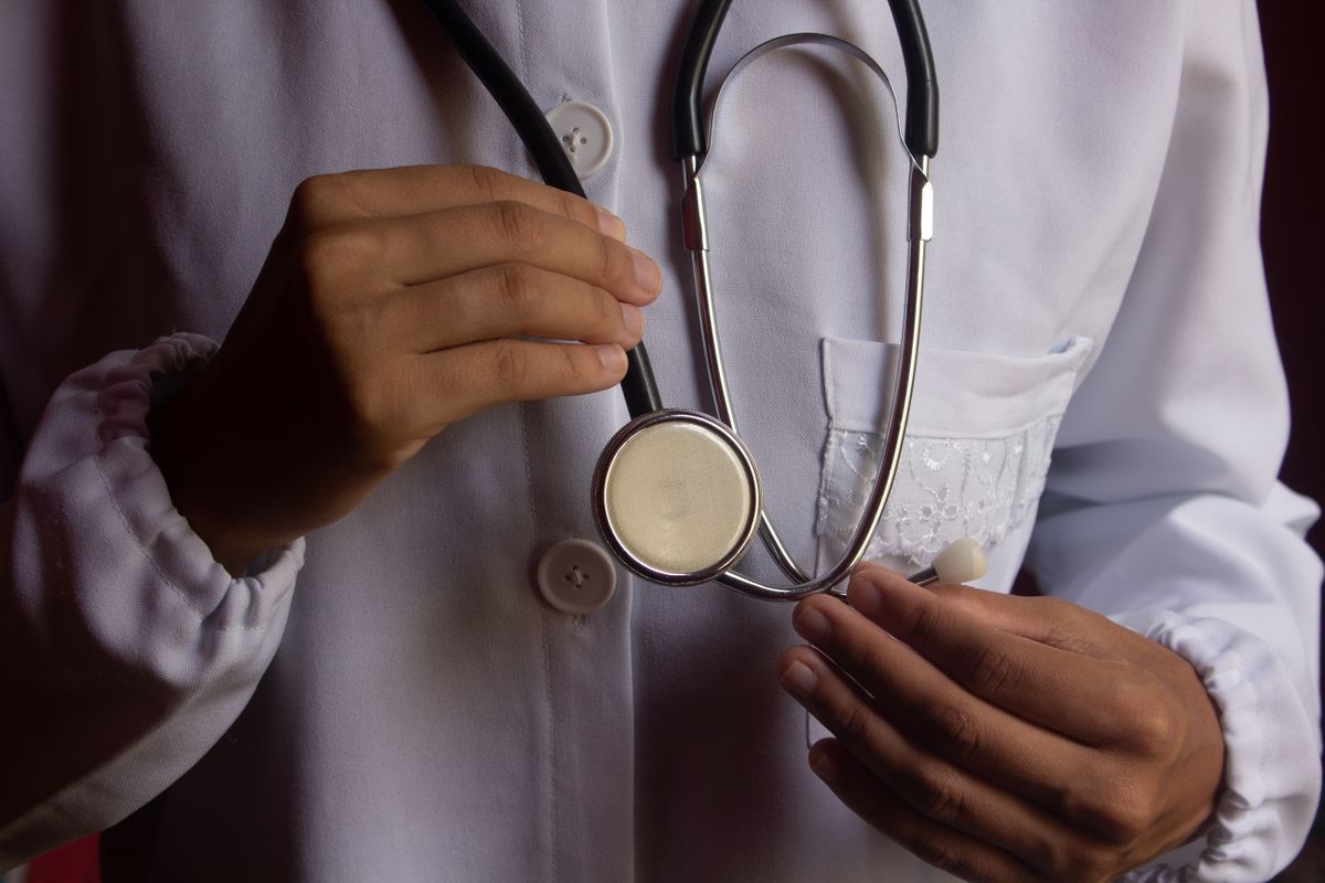 Mãos de um profissional de saúde segurando um estetoscópio